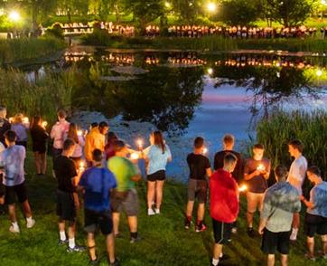 数十名学生在池塘外举着蜡烛.