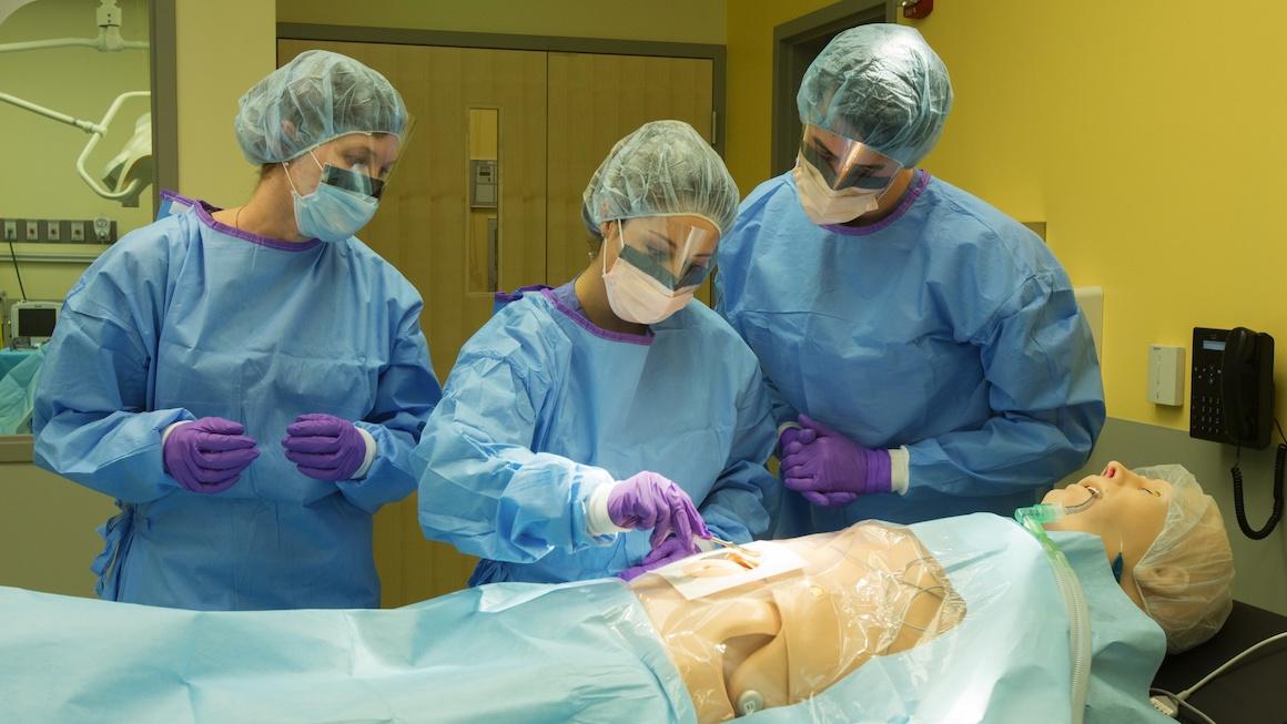 A group of Physician Assistant students work with a medical simulation dummy.