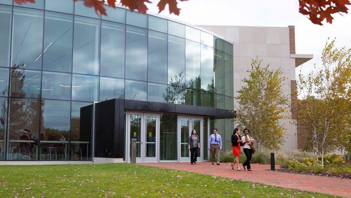 Four students walk out of the entrance to the Quinlan Brown Academic Innovation Center at Bryant University.